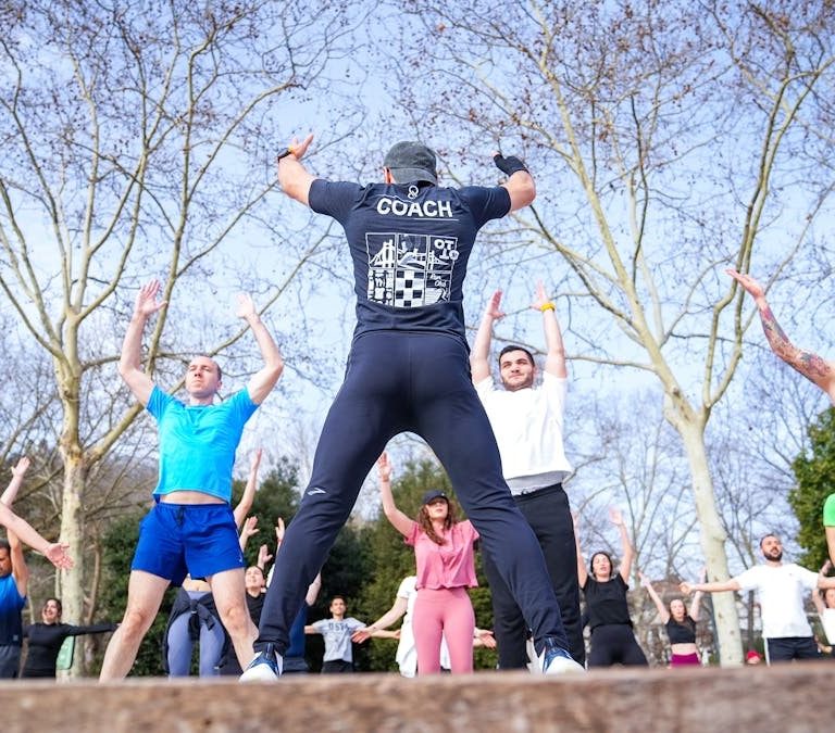 Group exercise session in a sunny Istanbul park led by a fitness coach outdoors.
